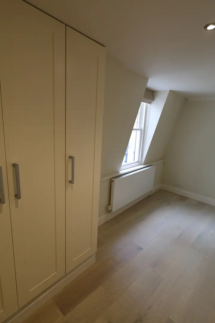 Fitted wardrobes beneath the apartment's sloping roofline