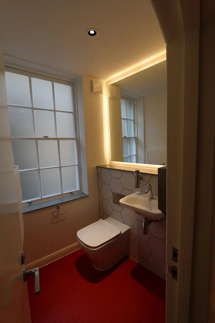 Restaurant washroom with integrated lighting and red flooring